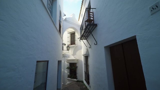 Smooth camera steady slide shot around old south Spain village narrow street, with white walls, beautiful facades with flowers, perfect for cinema digital composition or movie clips background