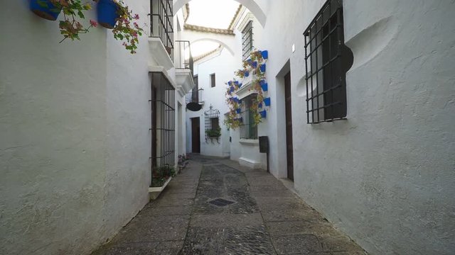 Smooth camera steady slide shot around old south Spain village narrow street, with white walls, beautiful facades with flowers, perfect for cinema digital composition or movie clips background