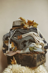 Blankets ready for autumn weather to provide warm coziness laying on the wooden vintage retro crate with vibrant leaves