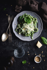 Green spinach pasta with cheese and pine nuts. Top view, dark food photo. Vertical. Homemade...