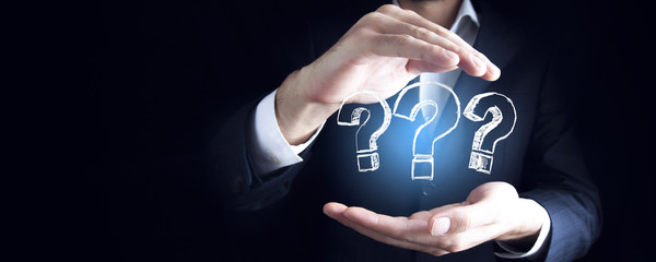 Hand holding question mark in palms on dark background