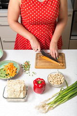 White girl close up on cutting carrot on wooden board