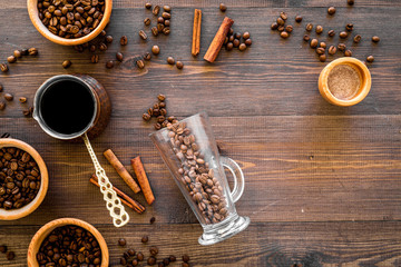 Make coffee in turkish coffee pot. Coffee beans, cinnamon on wooden background top view copyspace