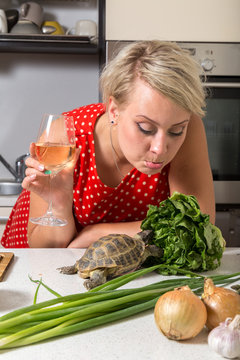 Girl mops surprised on tortoise who is eating salad