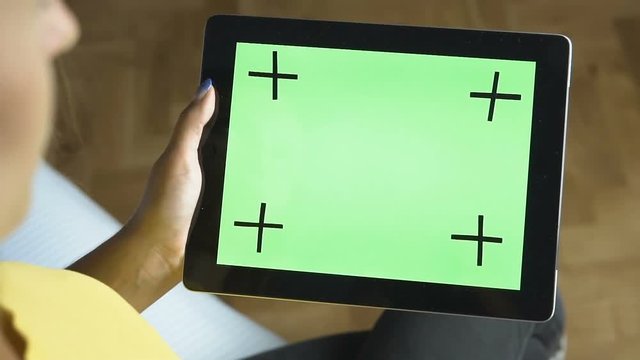 Young caucasian girl doing slide gestures on the flat green screen of her tablet, slow motion