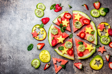 Fruit watermelon pizza with tropical fruits and berries - mango, tuna and mint on stone gray background. Pizza made of watermelon and fruits, top view