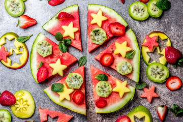 Fruit watermelon pizza with tropical fruits and berries - mango, tuna and mint on stone gray background. Pizza made of watermelon and fruits, top view