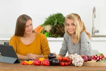 female friends cooking together following recipe on tablet