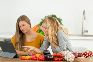 female friends cooking together following recipe on tablet