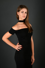 Fototapeta premium Young brunette lady in black dress posing on grey background