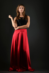 Naklejka premium Young brunette lady in black dress posing on grey background