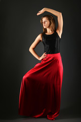 Young brunette lady in black dress posing on grey background