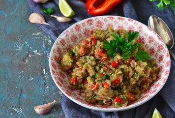 Snack salad of roasted eggplant with garlic and tomato on a concrete background