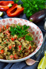 Snack salad of roasted eggplant with garlic and tomato on a concrete background