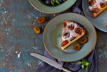 Homemade pie with plums on a concrete background
