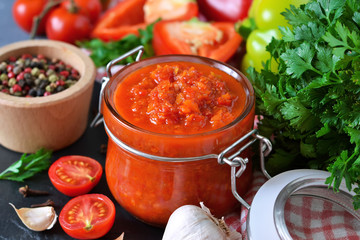 Adjika is a Georgian national sauce made of pepper, garlic and spices on a black background. Sauce. Food background.