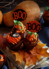 Halloween Cucpcakes with text topper decoration and orange cream. Candles and pumpkin background