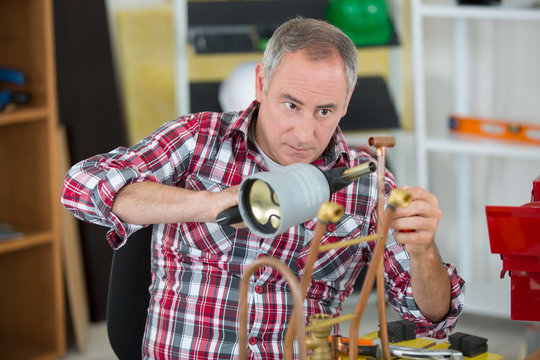 skilled tradesman is soldering a copper pipe
