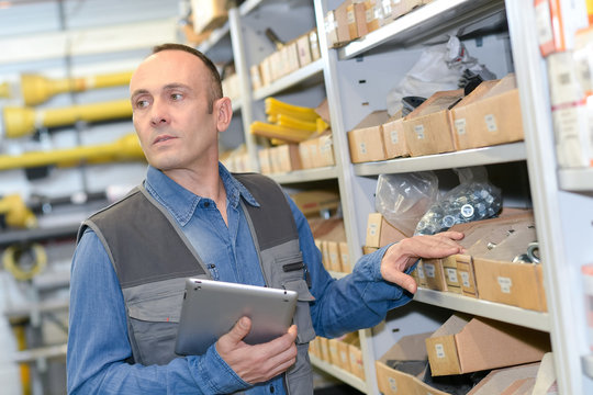 warehouse worker checking supplies in a tablet computer