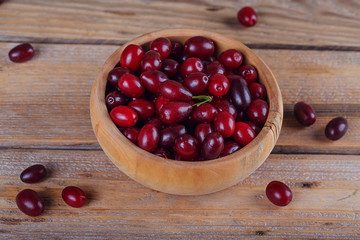 Fresh cornel berries on a wooden background.