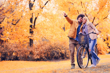 Smiling young couple with bicycle in autumn park 