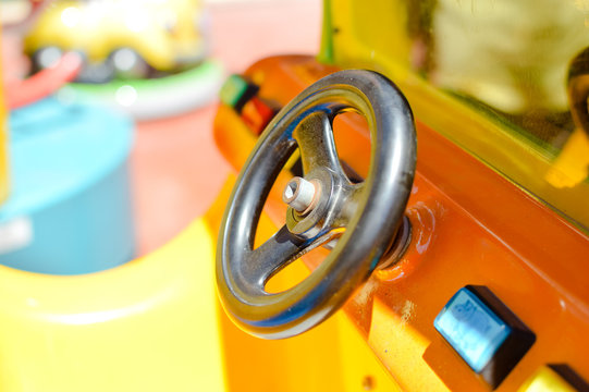 Closeup on children's machine steering wheel on the amusement leisure park background