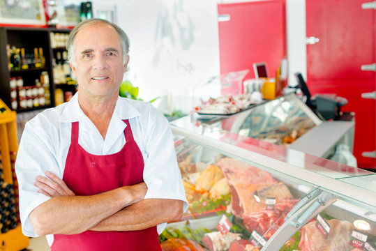 Butcher stood in shop with arms crossed