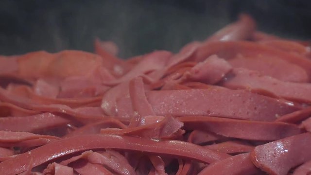 Chef preparing hamburger or sandwich in fast food restaurant with sliced sausages 
