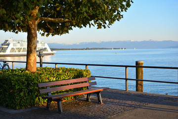 Promenade von Friedrichshafen, Fähre bei der Ausfahrt aus dem Hafen, Bank in der Abendsonne