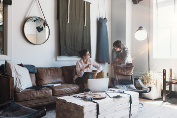 Two young business people work together in cozy loft work space. Team researching product and...