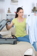Obraz premium young woman packing her red suitcase close up