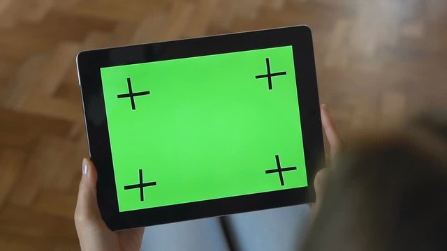Young caucasian girl does slide touching gestures on the green screen of her tablet, slow motion