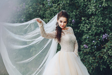 Fototapeta premium Attractive young bride in beautiful white dress posing on the nature background