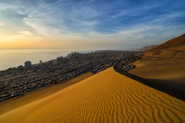 Stunning view to sand dunes, ocean and Iquique city at sunset
