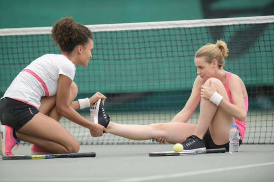 two tennis players stretching leg outdoors