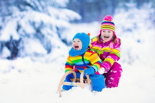 Kids on sleigh ride. Children sledding. Winter snow fun.