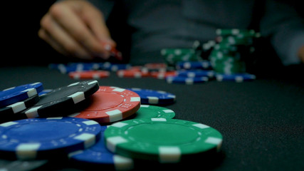 Throw the blue chips in poker. Blue and Red Playing Poker Chips in Reflective black Background. Closeup of poker chips in stacks on green felt card table surface in slow motion
