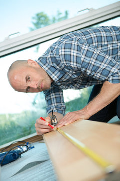man measuring a flooring plank