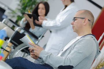 Man reading papers in medical waiting room