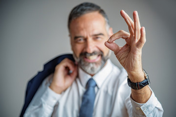 Senior business man giving approval, making an ok sign with his fingers