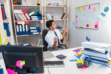 Businessman working in the office with piles of books and papers