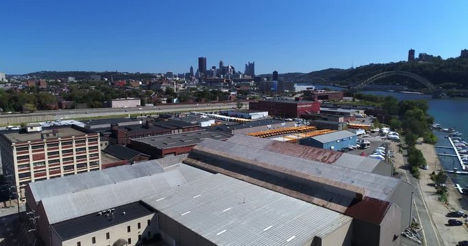 A mid-day aerial establishing shot of the Pittsburgh skyline with the warehouse business industrial park in the foreground.  	