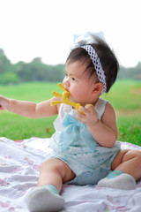 Asian Adorable baby girl playing with toy in park. Beautiful smiling cute baby