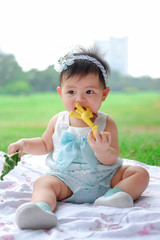 Asian Adorable baby girl playing with toy in park. Beautiful smiling cute baby