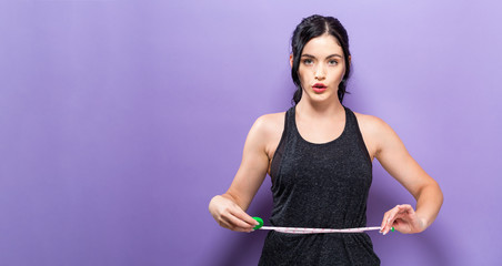 Young woman measuring her waist with a tape measure