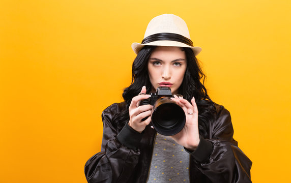  Young woman holding a camera on a yellow background
