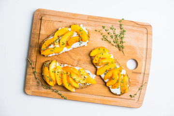 Bread with ricotta cheese and grilled peaches on the rustic background. Shallow depth of field. Selective focus.