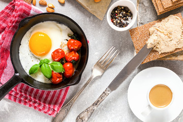 Breakfast - fried eggs from a tomato, coffee and a toast with fish paste on a gray concrete background. Top view.
