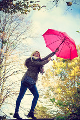 Woman walking in park with umbrella, strong wind