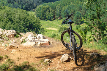 Fototapeta na wymiar the bike stands on a hill on the edge of the cliff by the river, amid wildlife around the forest